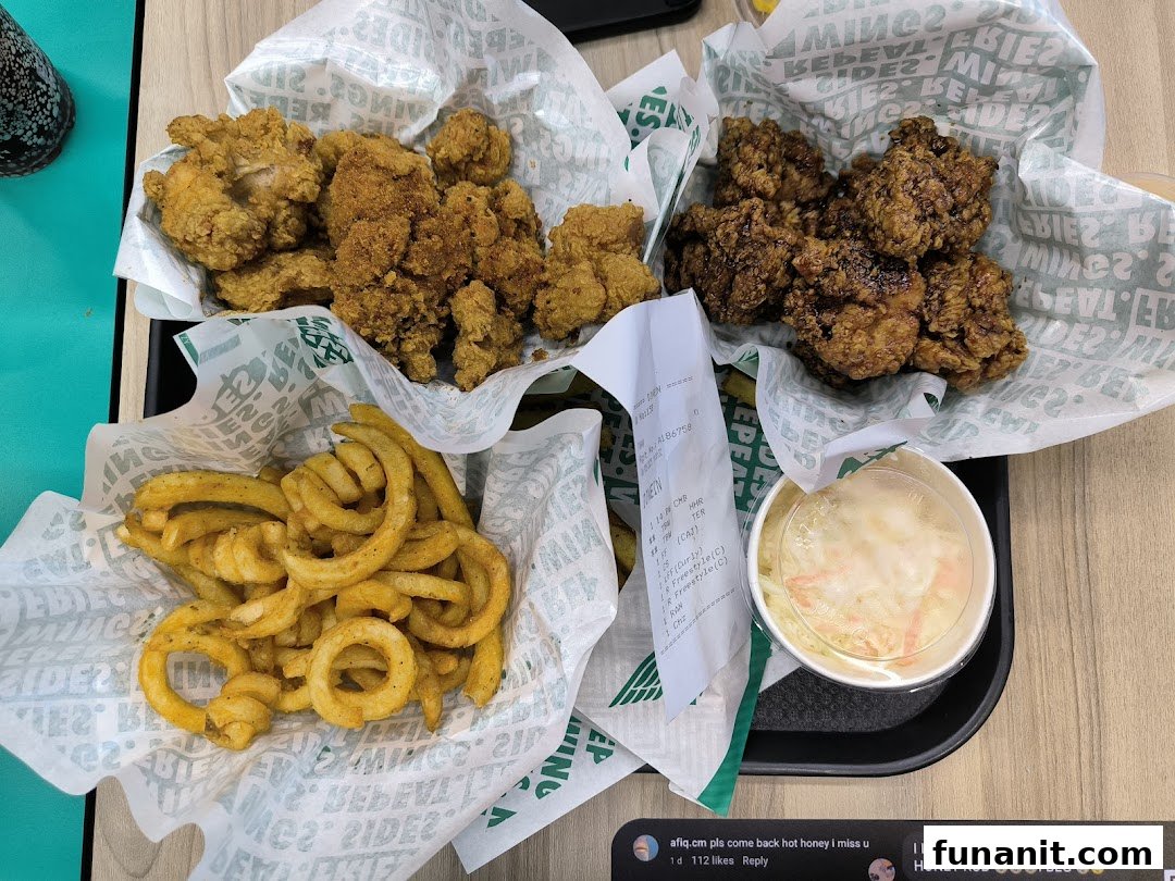 A delicious spread of Wingstop's crispy chicken, golden curly fries, and refreshing coleslaw on a tray.