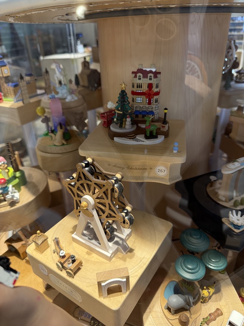 A close-up view of intricate wooden music boxes and crafts displayed in a glass case.