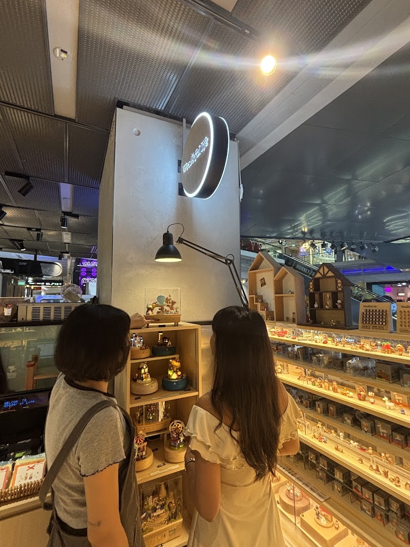 Two customers browse intricate music boxes and miniature wooden figures inside Wooderful Life Singapore.