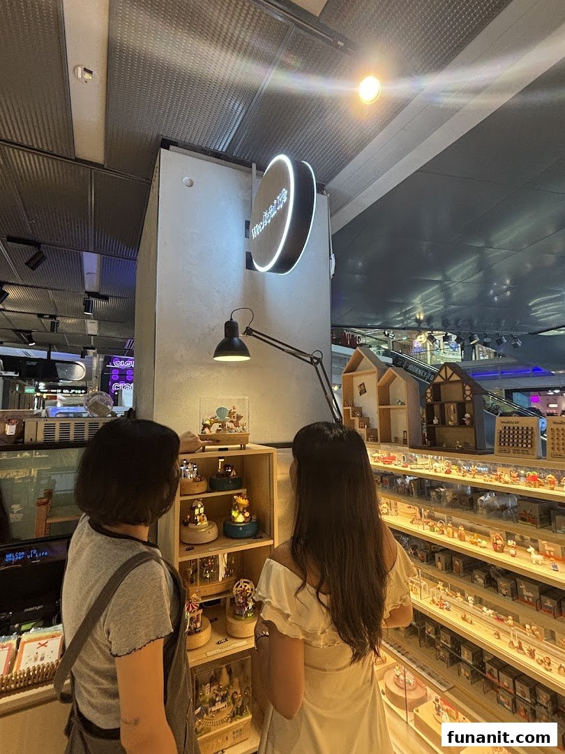 Two customers browse intricate music boxes and miniature wooden figures inside Wooderful Life Singapore.