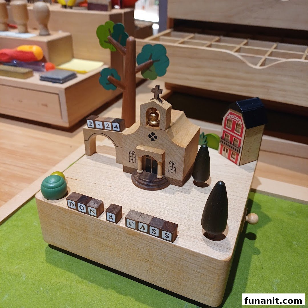 A beautifully crafted wooden music box featuring a church, trees, and personalized name blocks 'DON & CASS'.