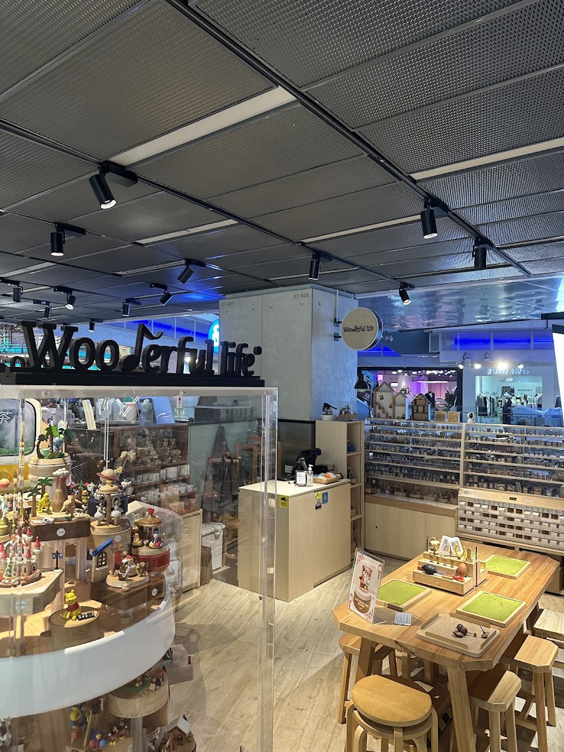 Interior view of Wooderful Life Singapore, showcasing intricate wooden music boxes, crafts, and a DIY workshop table.