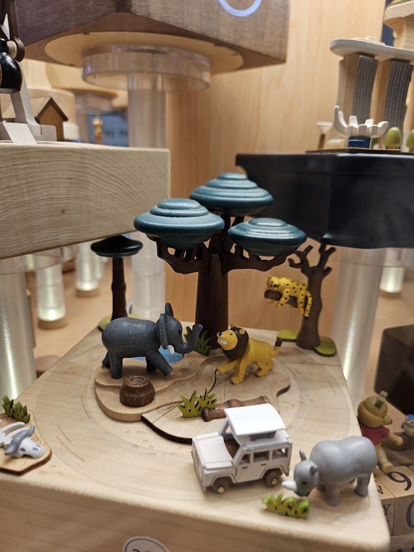 A detailed wooden display featuring miniature safari animals, a vehicle, and trees, likely part of a music box.