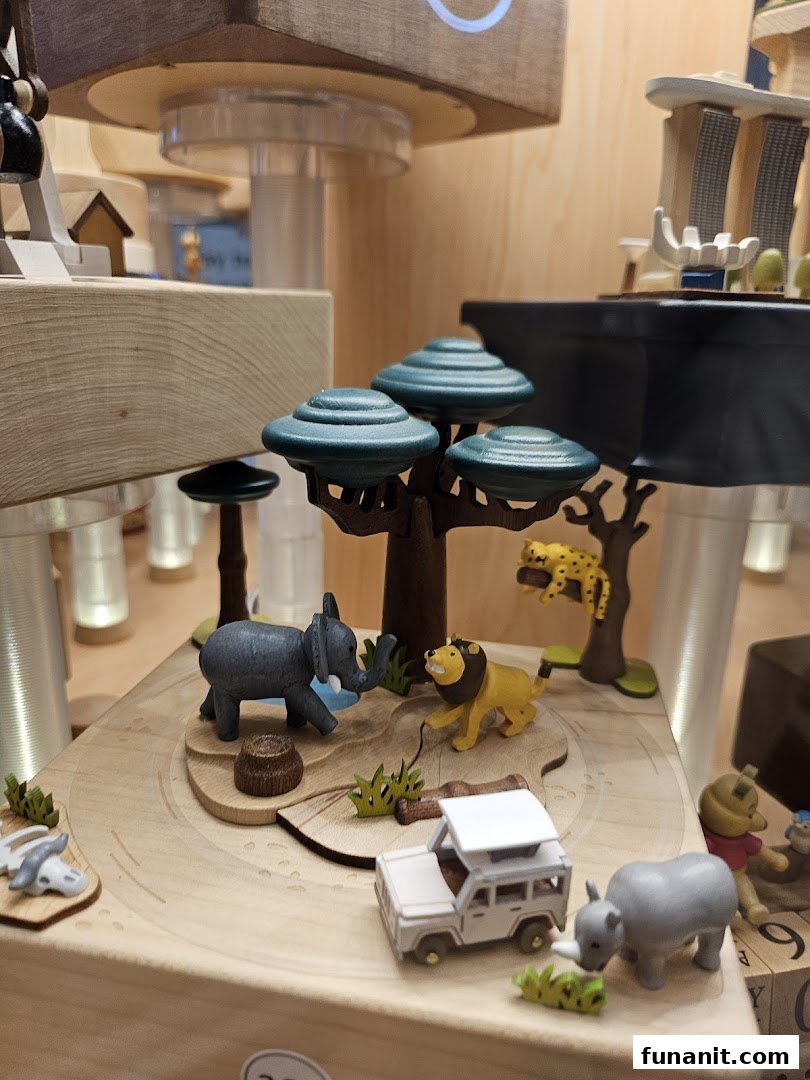 A detailed wooden display featuring miniature safari animals, a vehicle, and trees, likely part of a music box.