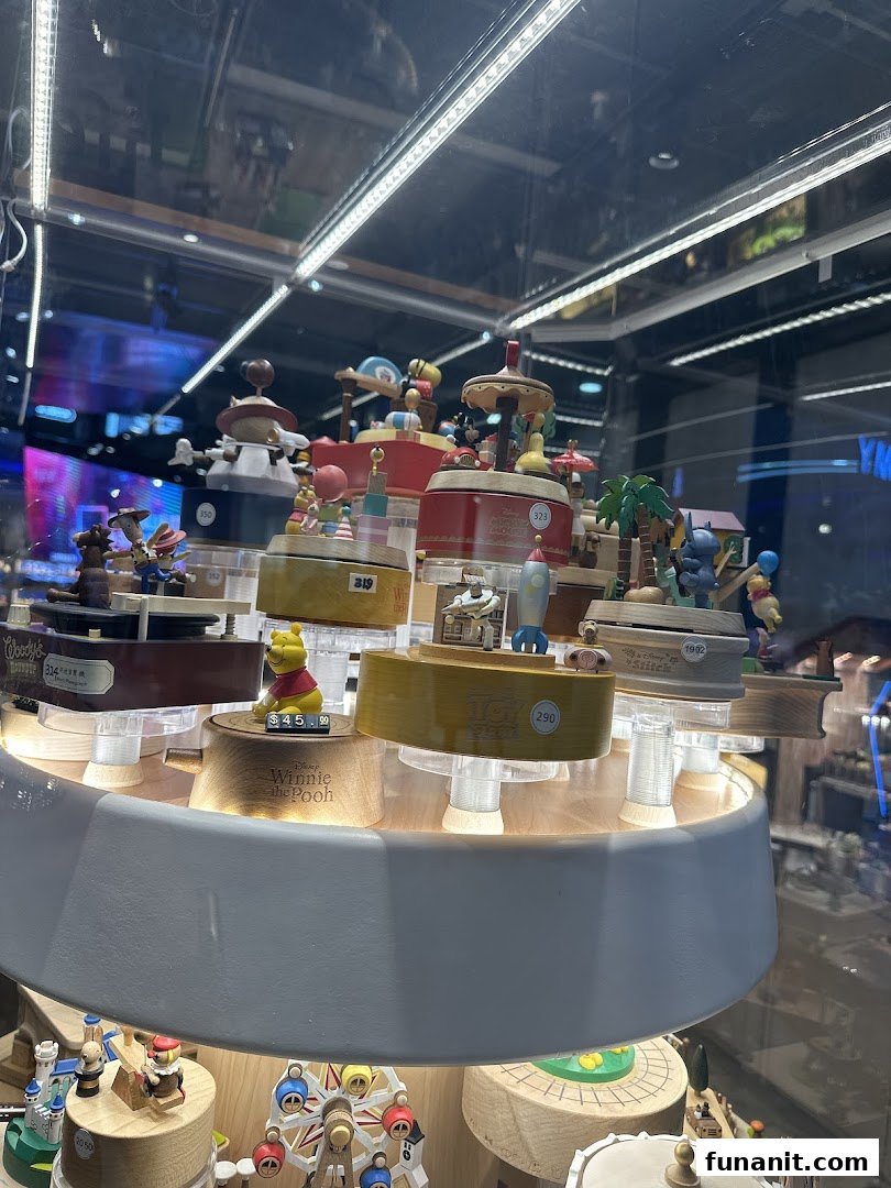 A display of intricately crafted wooden music boxes and figurines, including Winnie the Pooh, in a brightly lit retail case.