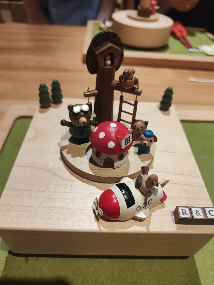 Close-up of a charming wooden music box featuring bears, a mushroom house, and an airplane.