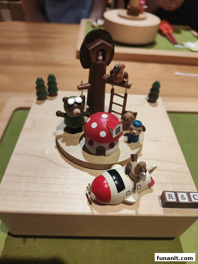 Close-up of a charming wooden music box featuring bears, a mushroom house, and an airplane.