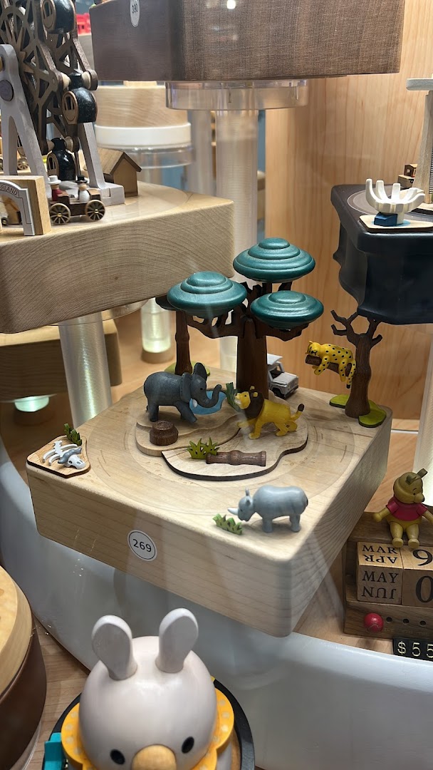 Detailed wooden safari-themed music box with animals and trees on display.