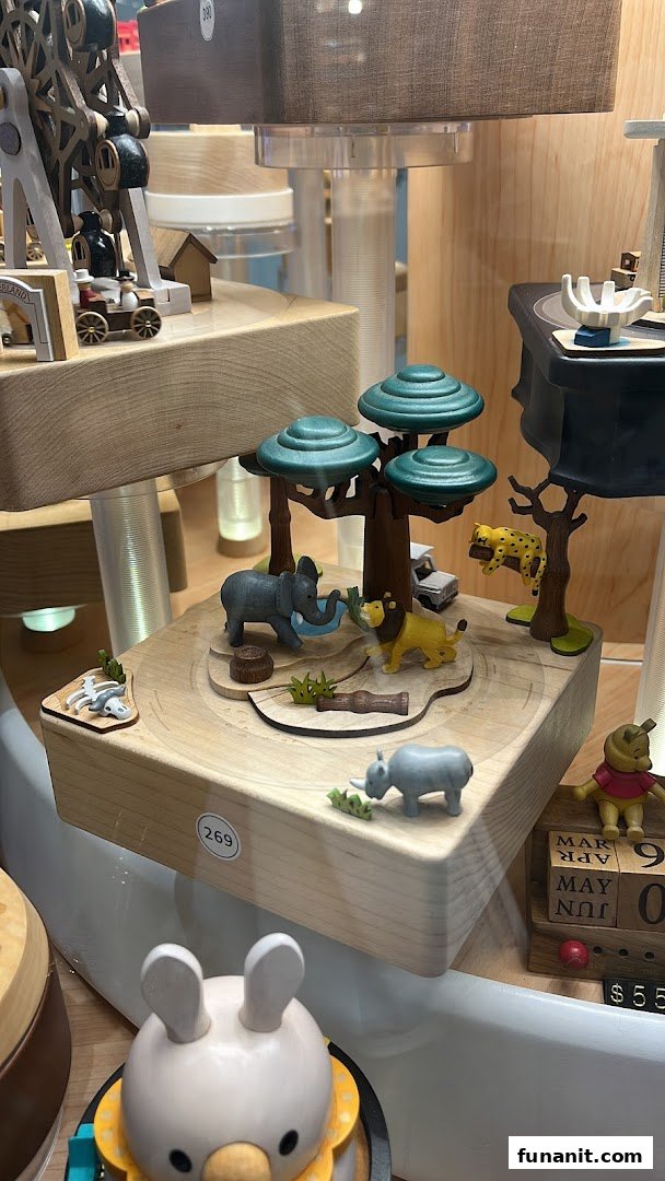 Detailed wooden safari-themed music box with animals and trees on display.