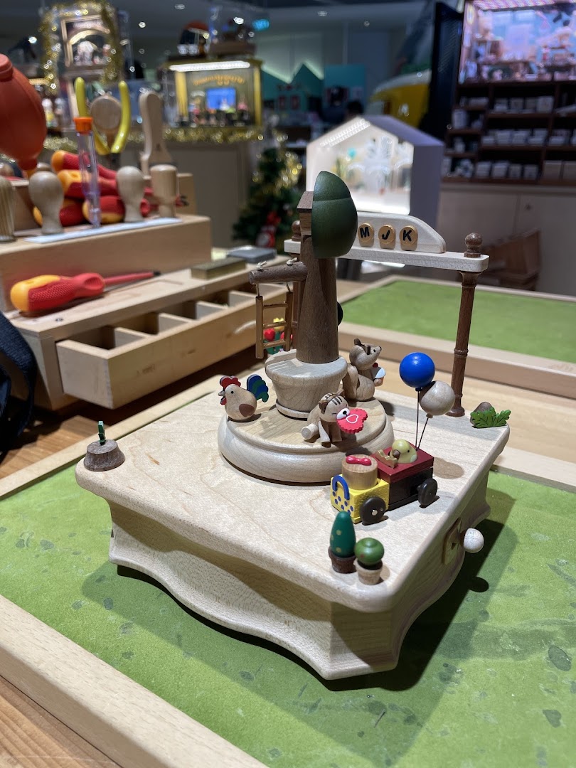 A detailed wooden music box or craft featuring charming animal figures and a miniature train.