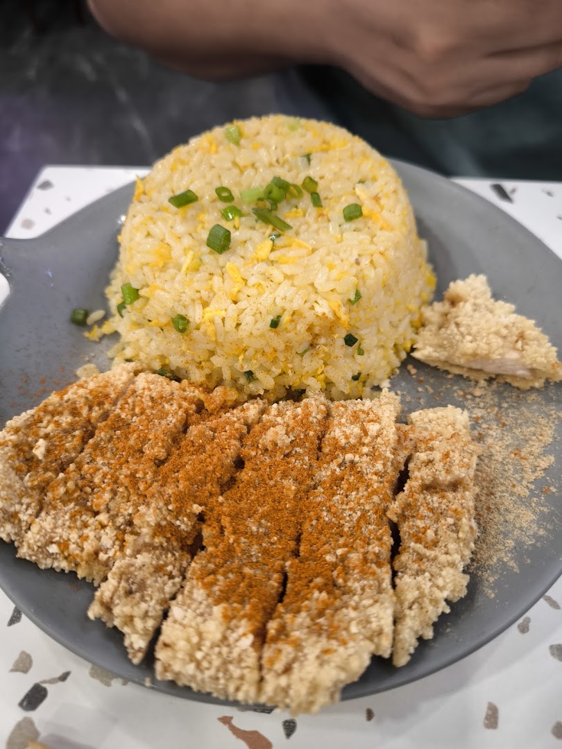 A plate of golden fried rice with spring onions, served alongside a crispy, seasoned Taiwanese chicken cutlet.