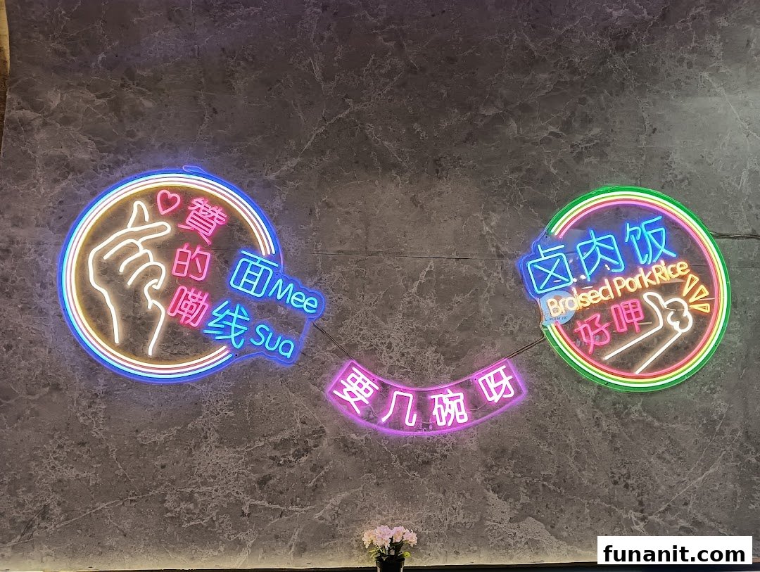 Vibrant neon signs on a grey wall promoting Mee Sua and Braised Pork Rice with playful hand gestures.