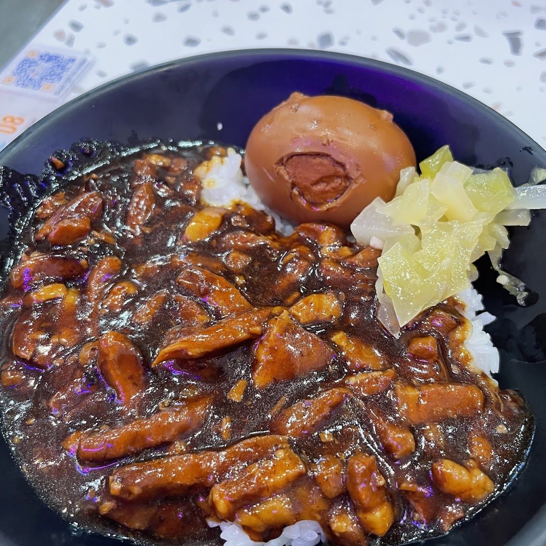 A close-up of a delicious bowl of Taiwanese braised pork rice (Lu Rou Fan) with a braised egg and pickled vegetables.