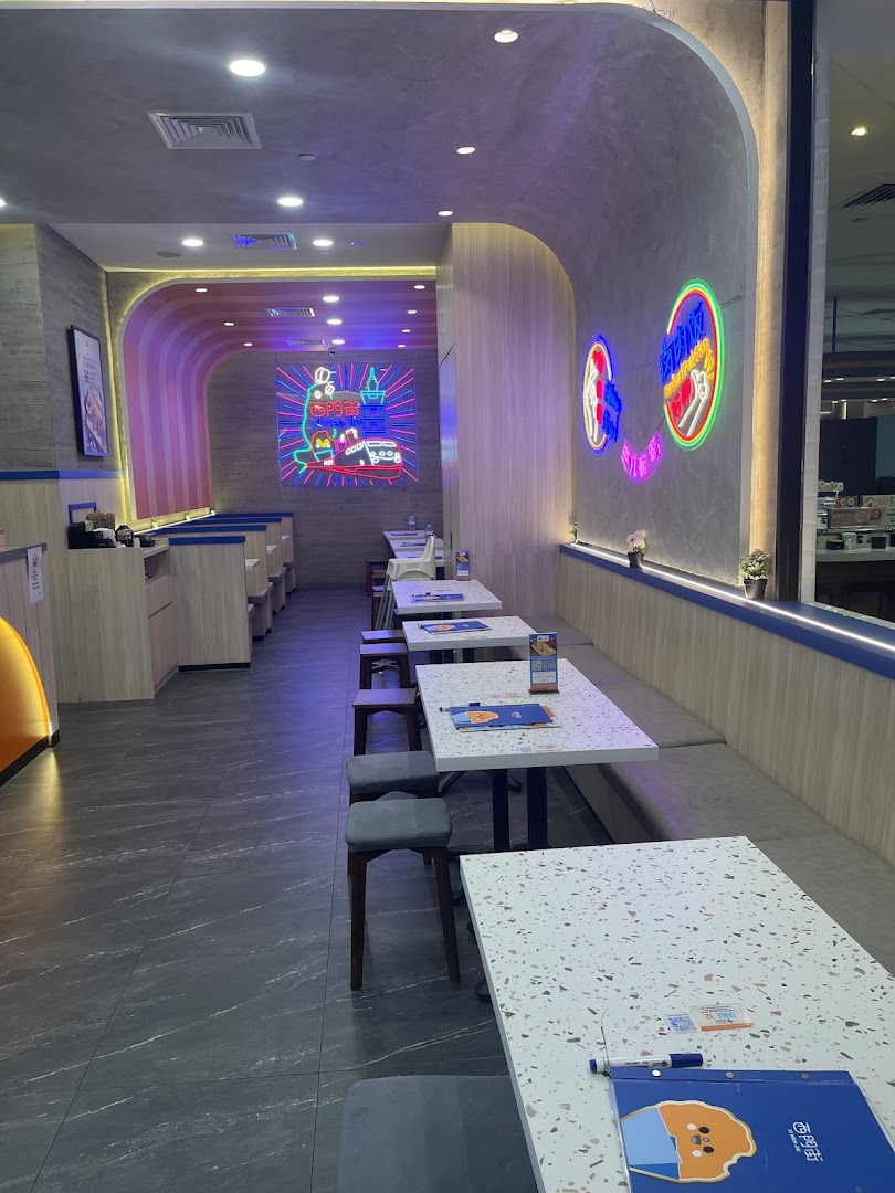 Modern interior of a Taiwanese restaurant featuring comfortable seating, terrazzo tables, and vibrant neon wall art.