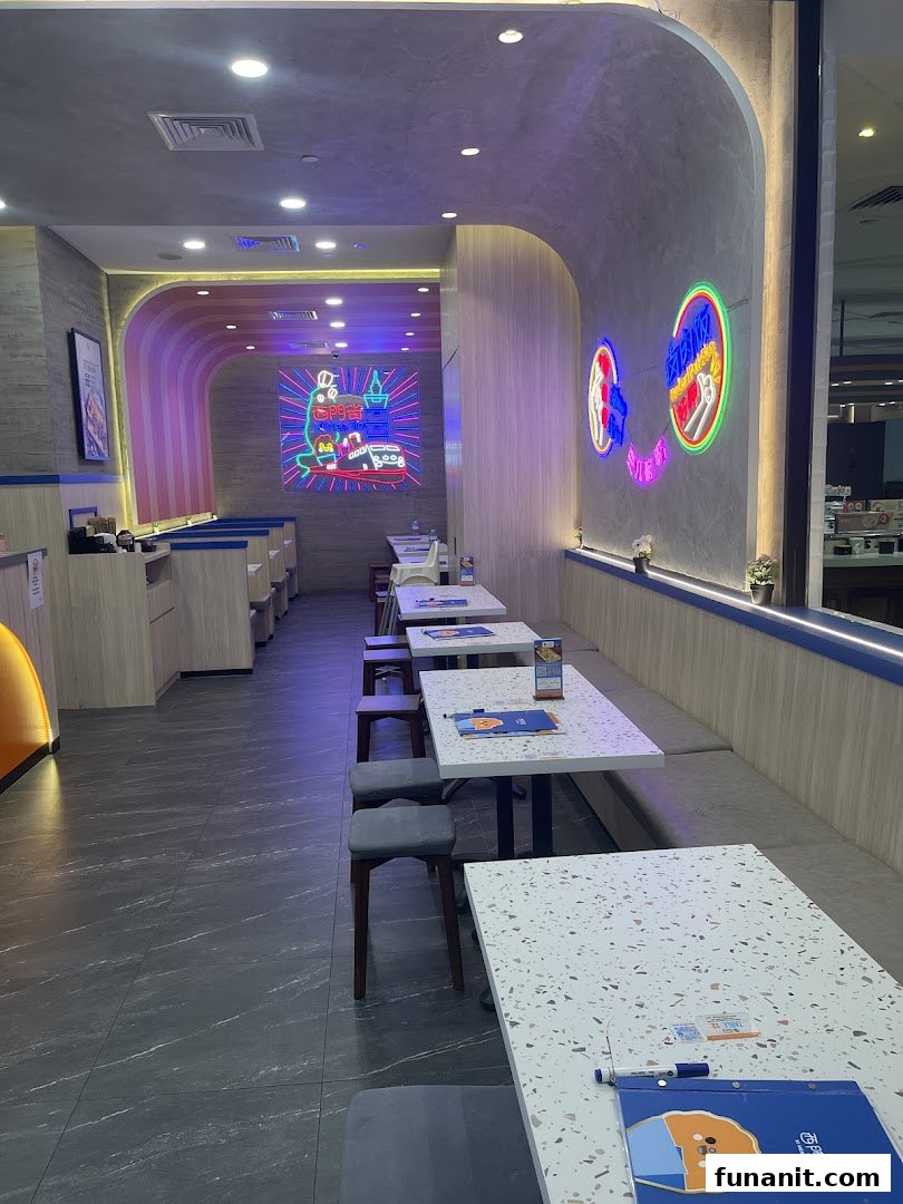 Modern interior of a Taiwanese restaurant featuring comfortable seating, terrazzo tables, and vibrant neon wall art.