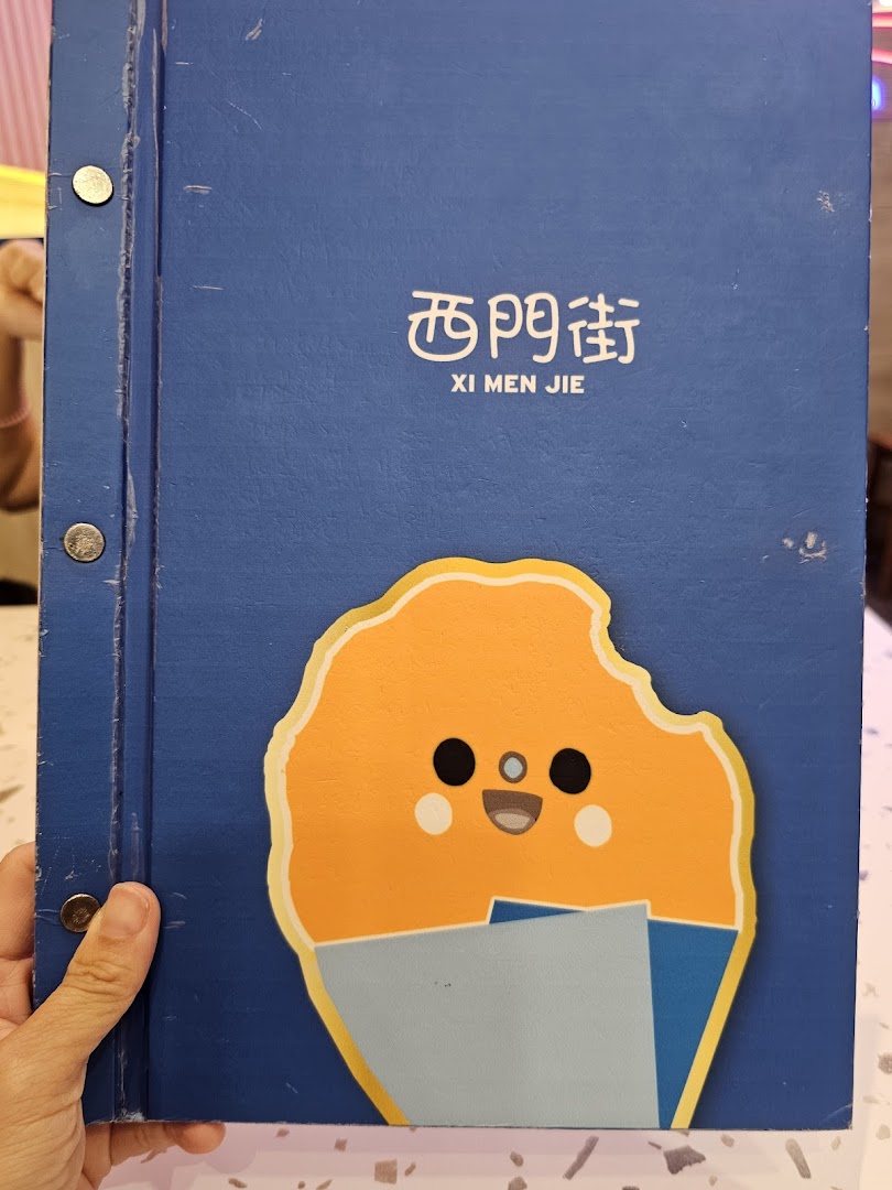 The blue cover of Xi Men Jie's menu features a cute cartoon character and the shop's name.