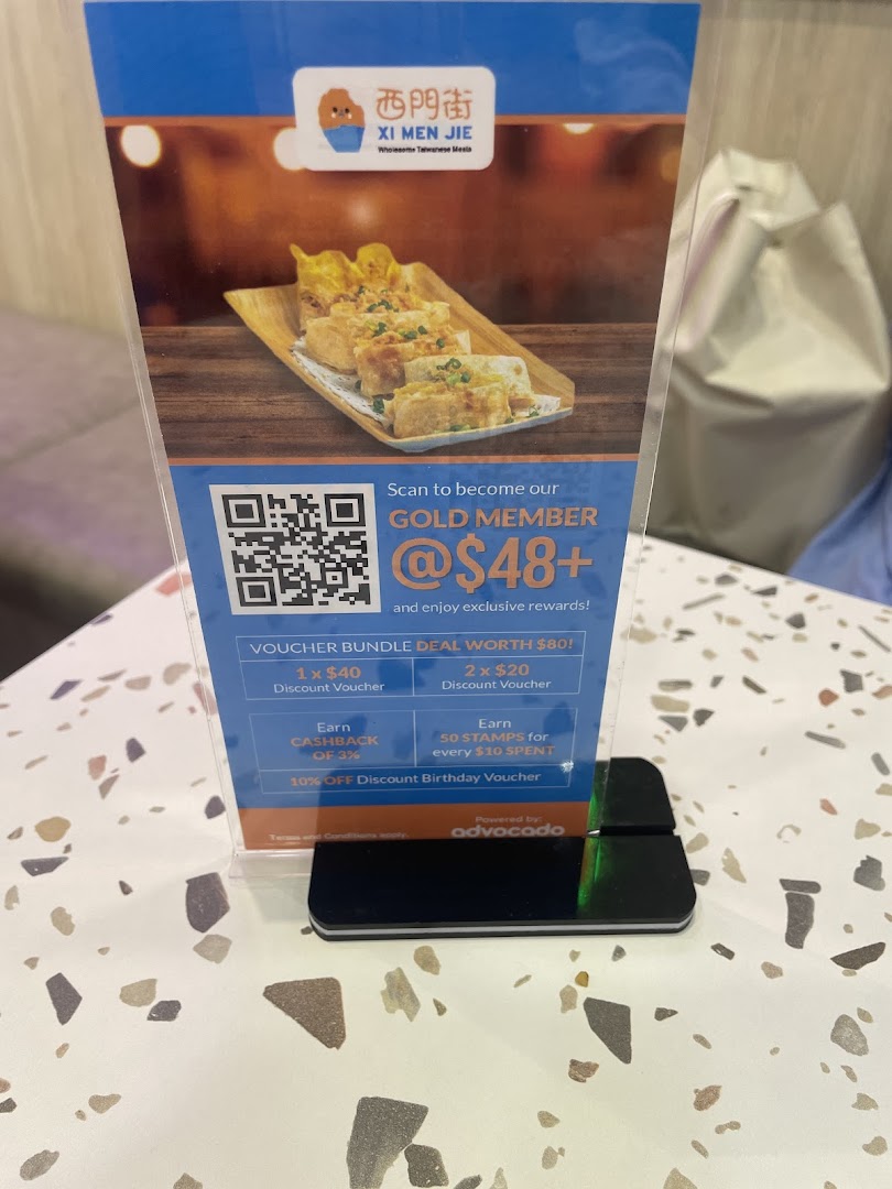 A standee promoting Xi Men Jie's Gold Member program with exclusive rewards and a food image.