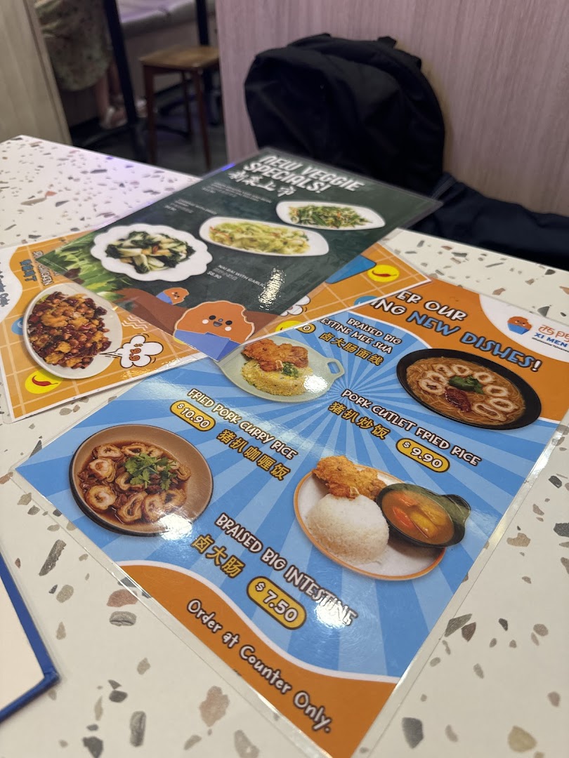 Close-up of laminated menu cards displaying various Taiwanese dishes and their prices on a speckled table.
