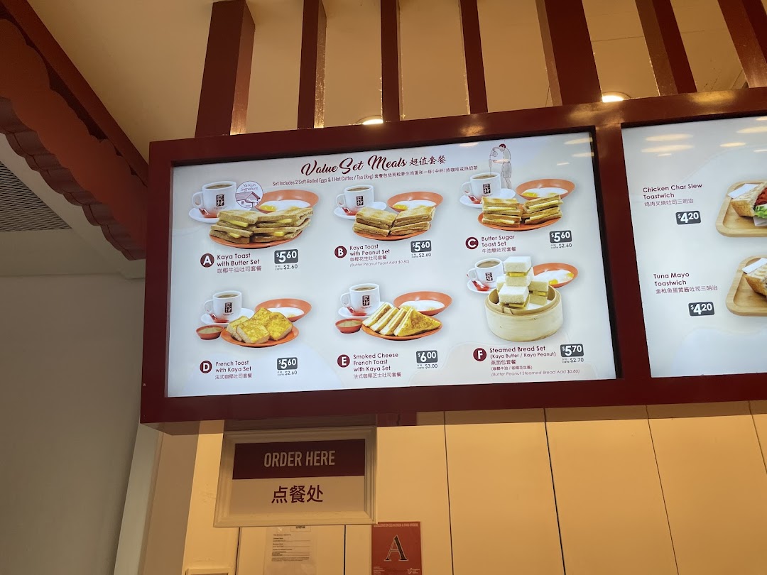 A brightly lit menu board displaying various breakfast sets and toastwiches with prices and images.