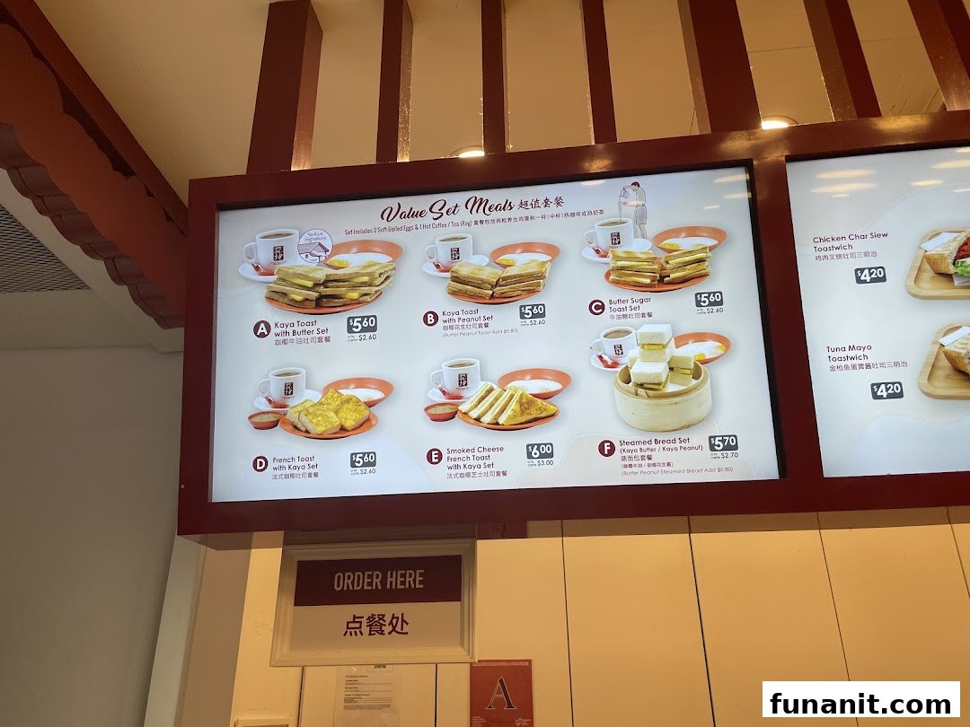 A brightly lit menu board displaying various breakfast sets and toastwiches with prices and images.