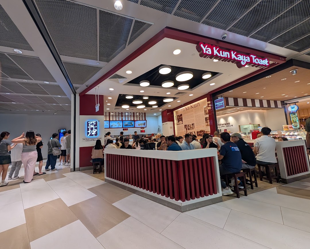 Customers enjoying traditional Singaporean breakfast and coffee inside a bustling Ya Kun Kaya Toast outlet.