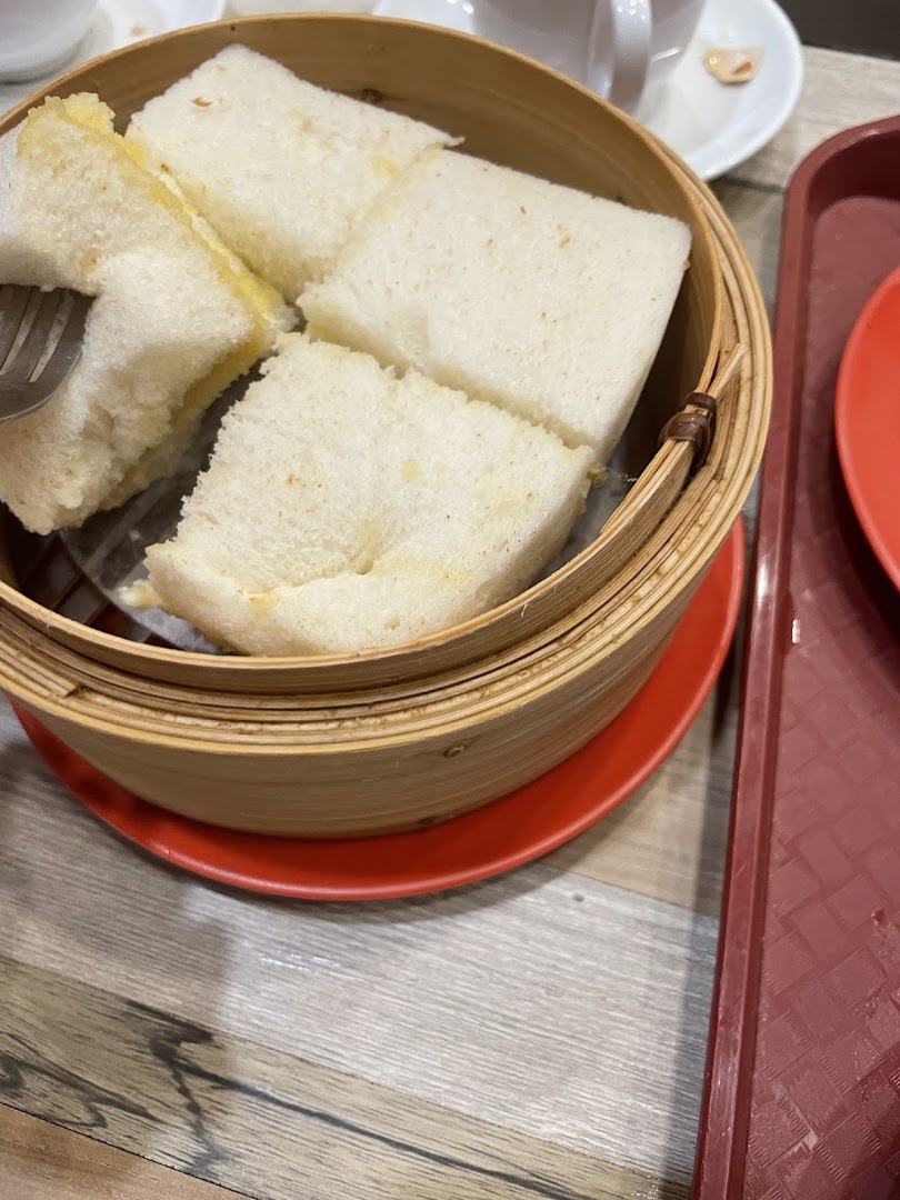 Close-up of fluffy steamed bread served in a traditional bamboo steamer at Ya Kun Kaya Toast.