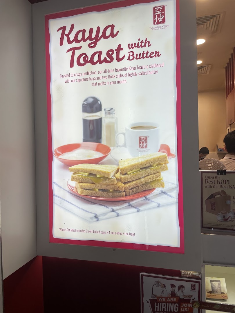 A bright promotional poster for Ya Kun Kaya Toast with butter, showing the dish, coffee, and eggs.