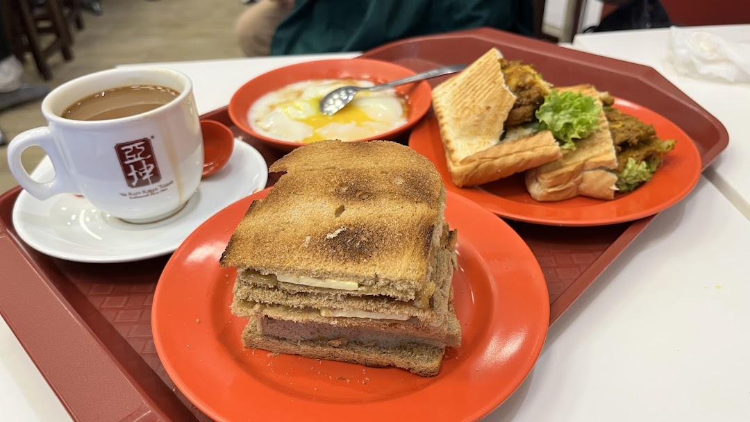 A tray featuring traditional Singaporean breakfast items: kaya toast, soft-boiled eggs, and coffee.