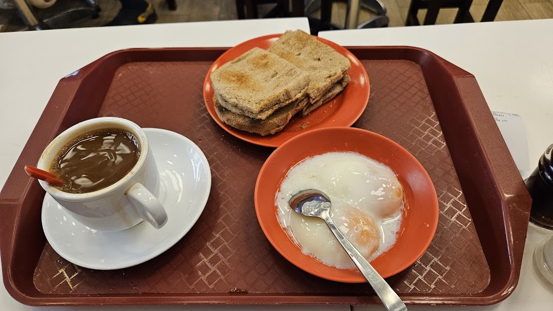 A traditional Singaporean breakfast set featuring kaya toast, soft-boiled eggs, and a cup of coffee.