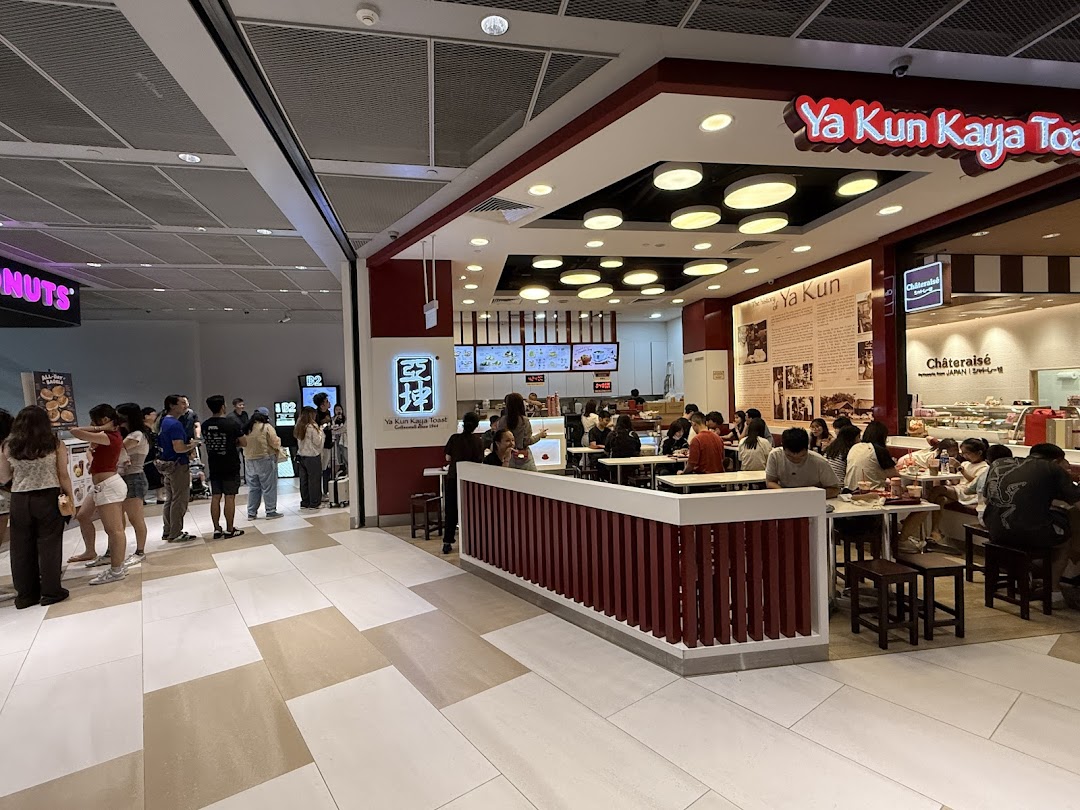 A bustling interior view of Ya Kun Kaya Toast with customers dining and a queue forming nearby.