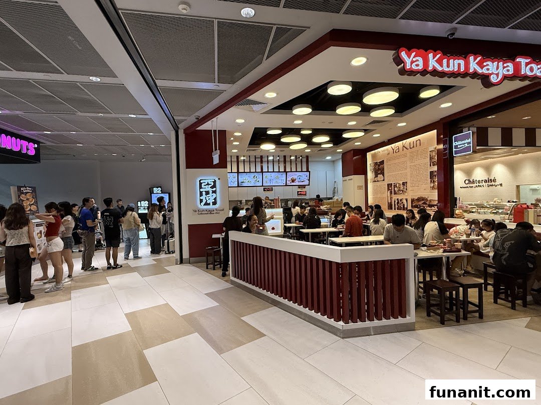 A bustling interior view of Ya Kun Kaya Toast with customers dining and a queue forming nearby.