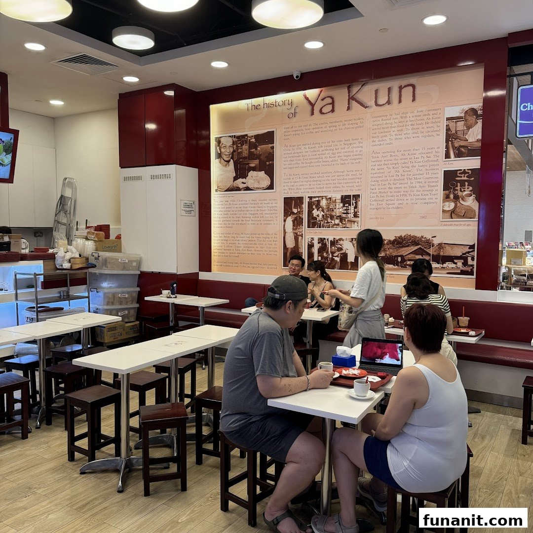 Customers enjoy traditional kaya toast and coffee in the cozy interior of Ya Kun Kaya Toast, featuring a historical wall display.
