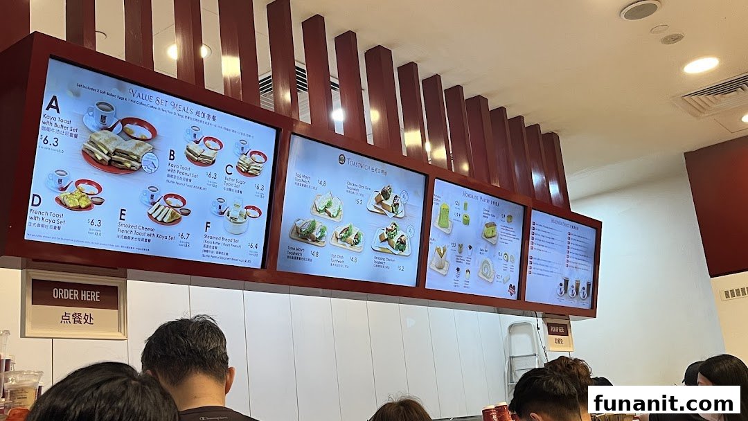 Digital menu boards at Ya Kun Kaya Toast displaying various breakfast sets, toastwiches, and pastries.