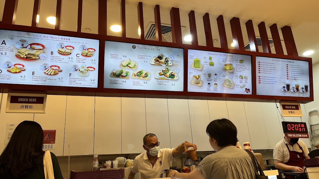 Digital menu boards displaying various toast sets, sandwiches, pastries, and beverages at Ya Kun Kaya Toast.