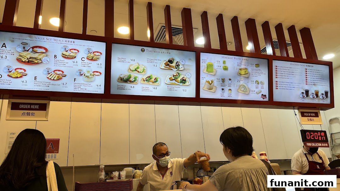 Digital menu boards displaying various toast sets, sandwiches, pastries, and beverages at Ya Kun Kaya Toast.