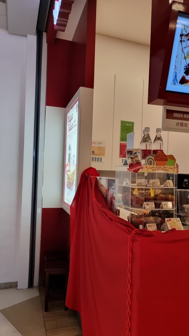 A counter area at Ya Kun Kaya Toast featuring a display of pastries and a prominent brand sign.