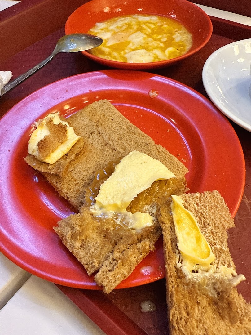 A classic Ya Kun Kaya Toast set featuring kaya toast with butter and a bowl of soft-boiled eggs.