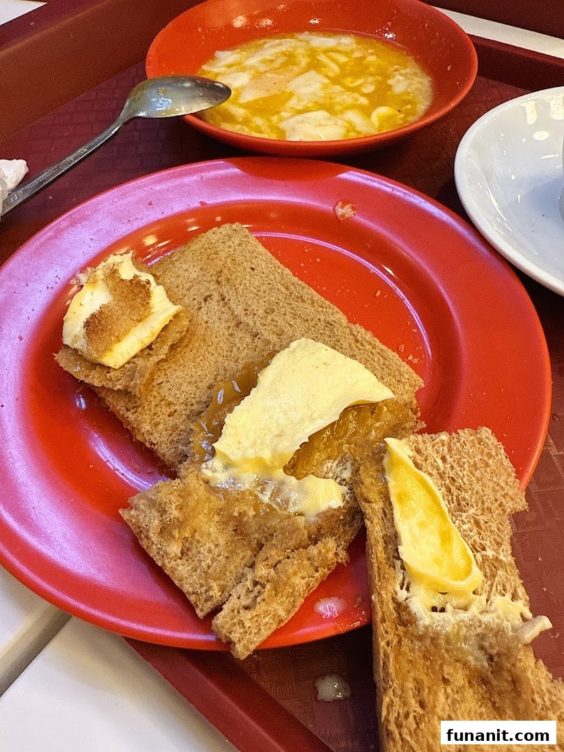 A classic Ya Kun Kaya Toast set featuring kaya toast with butter and a bowl of soft-boiled eggs.