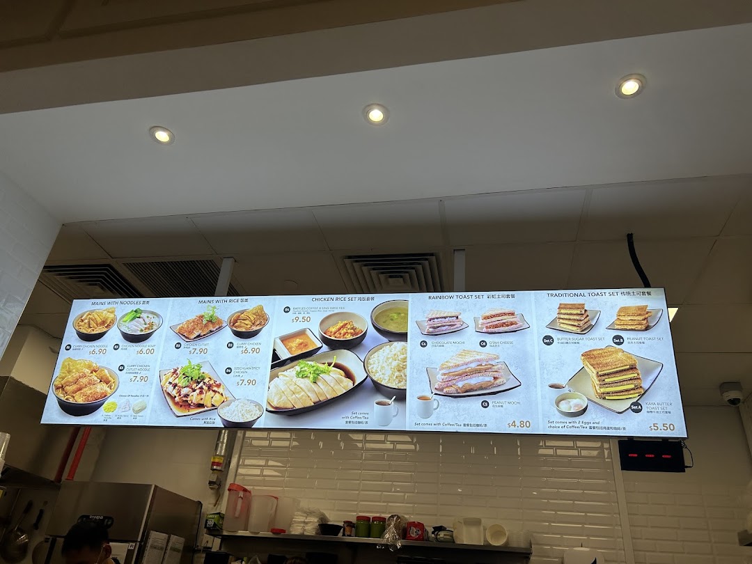A digital menu board displaying various toast sets, noodle dishes, and rice meals with prices.