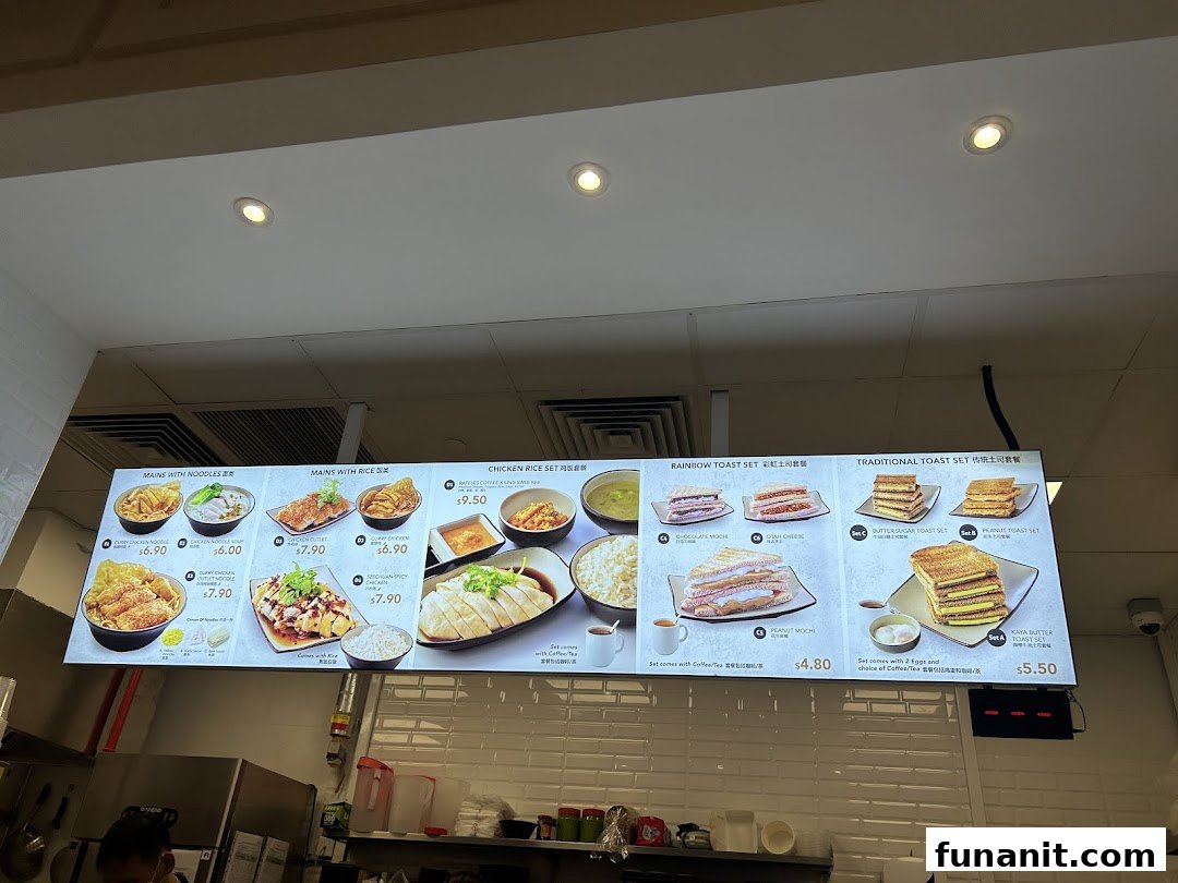 A digital menu board displaying various toast sets, noodle dishes, and rice meals with prices.