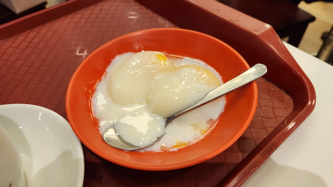 A close-up of two perfectly soft-boiled eggs in an orange bowl on a red tray.
