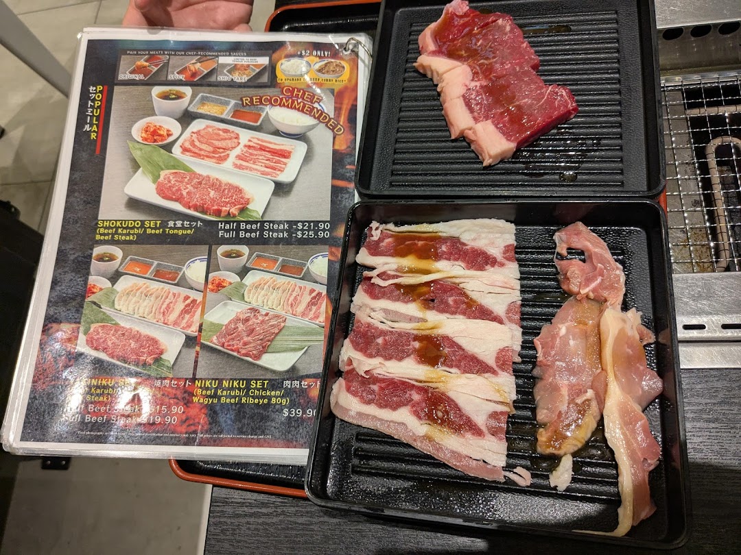 Menu displaying yakiniku meat sets and raw beef/chicken cuts on trays for grilling.
