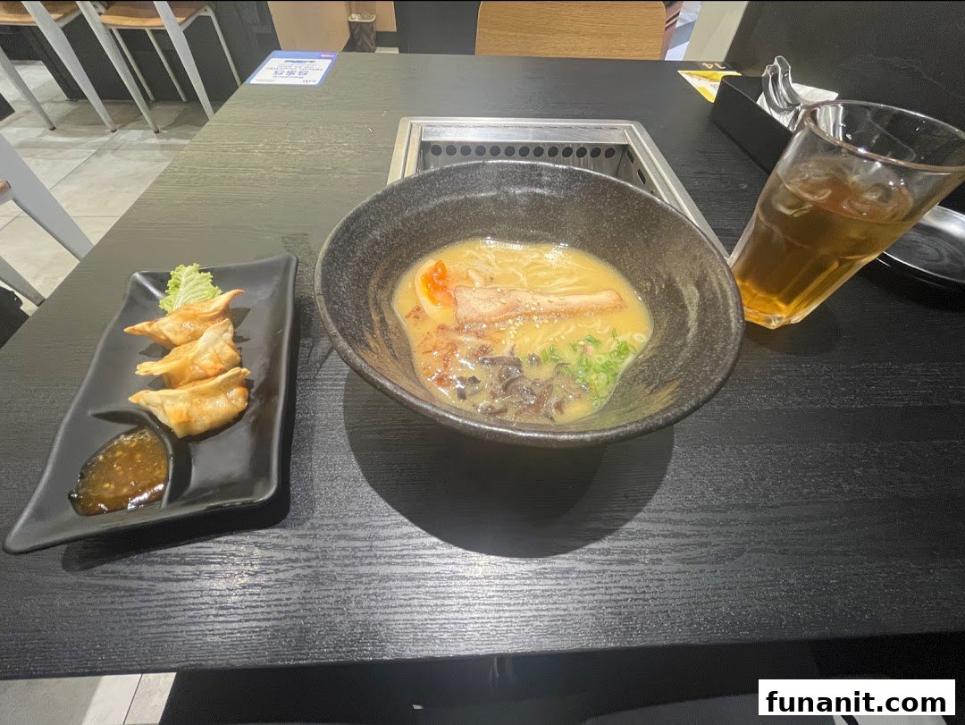 A delicious bowl of ramen and gyoza served on a black table with a refreshing drink.