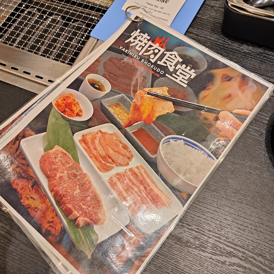 A close-up of a Yakiniku Shokudo menu cover featuring various cuts of raw meat, rice, and sauces.