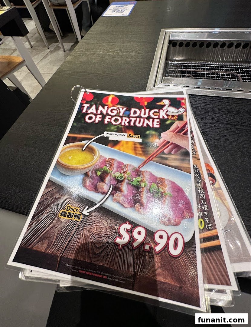 A close-up of a menu page featuring 'Tangy Duck of Fortune' with its price, on a restaurant table.