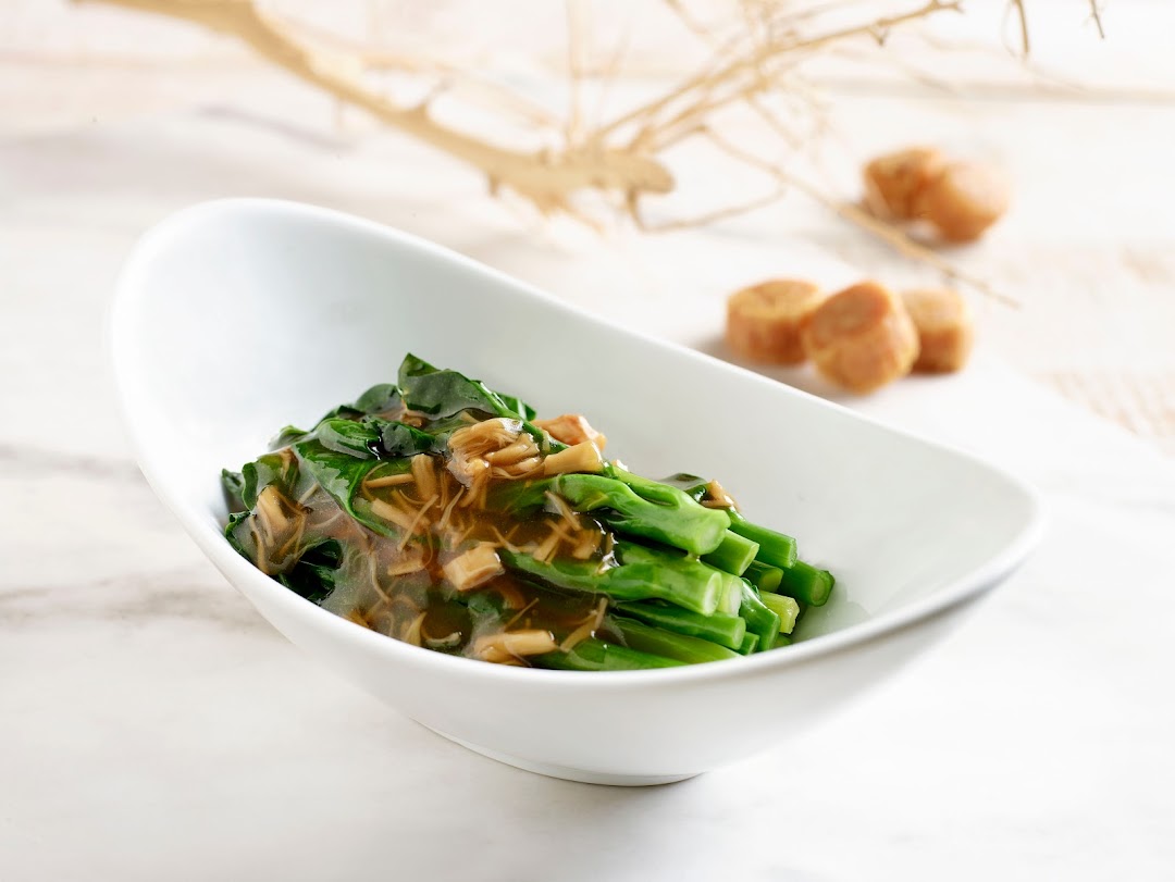 A white bowl filled with vibrant green vegetables topped with a savory brown sauce.