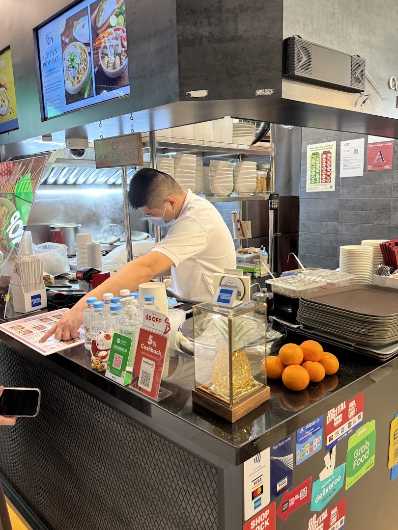 A chef prepares food behind a counter at Yan Ji Gourmet Seafood Soup, with a digital menu and payment options visible.