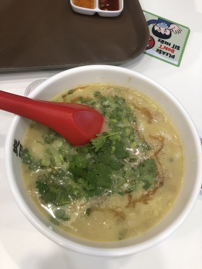 A close-up of a steaming bowl of gourmet seafood soup, garnished with spring onions and cilantro.