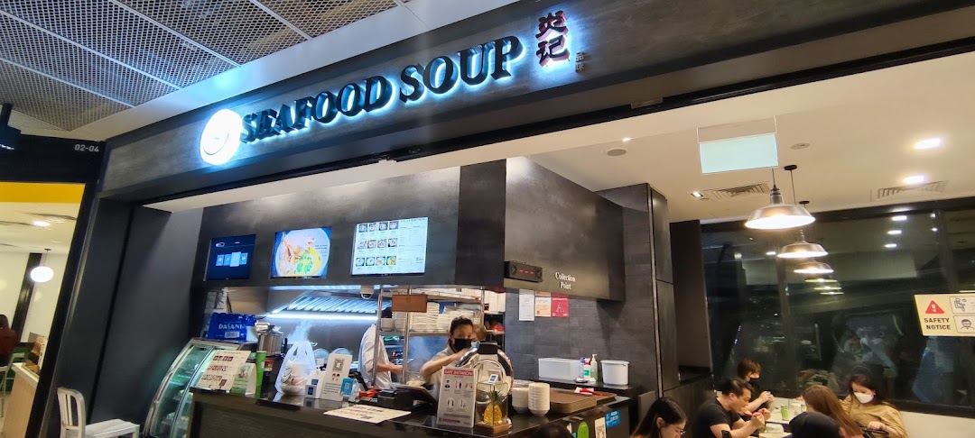 The image captures the vibrant shop front of Yan Ji Gourmet Seafood Soup, featuring its illuminated signage and bustling counter.