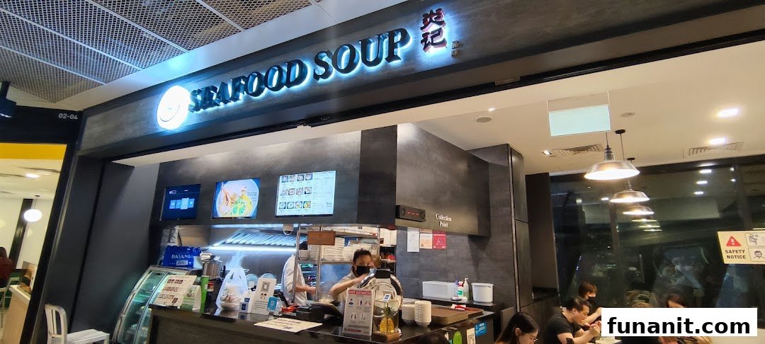 The image captures the vibrant shop front of Yan Ji Gourmet Seafood Soup, featuring its illuminated signage and bustling counter.